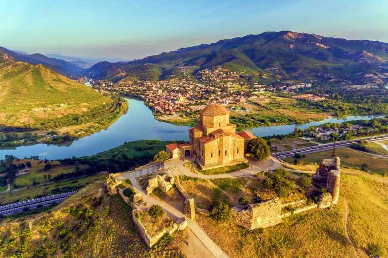 Jvari Monastery perched on hilltop overlooking Mtkvari River valley with mountains and town of Mtskheta in Georgia